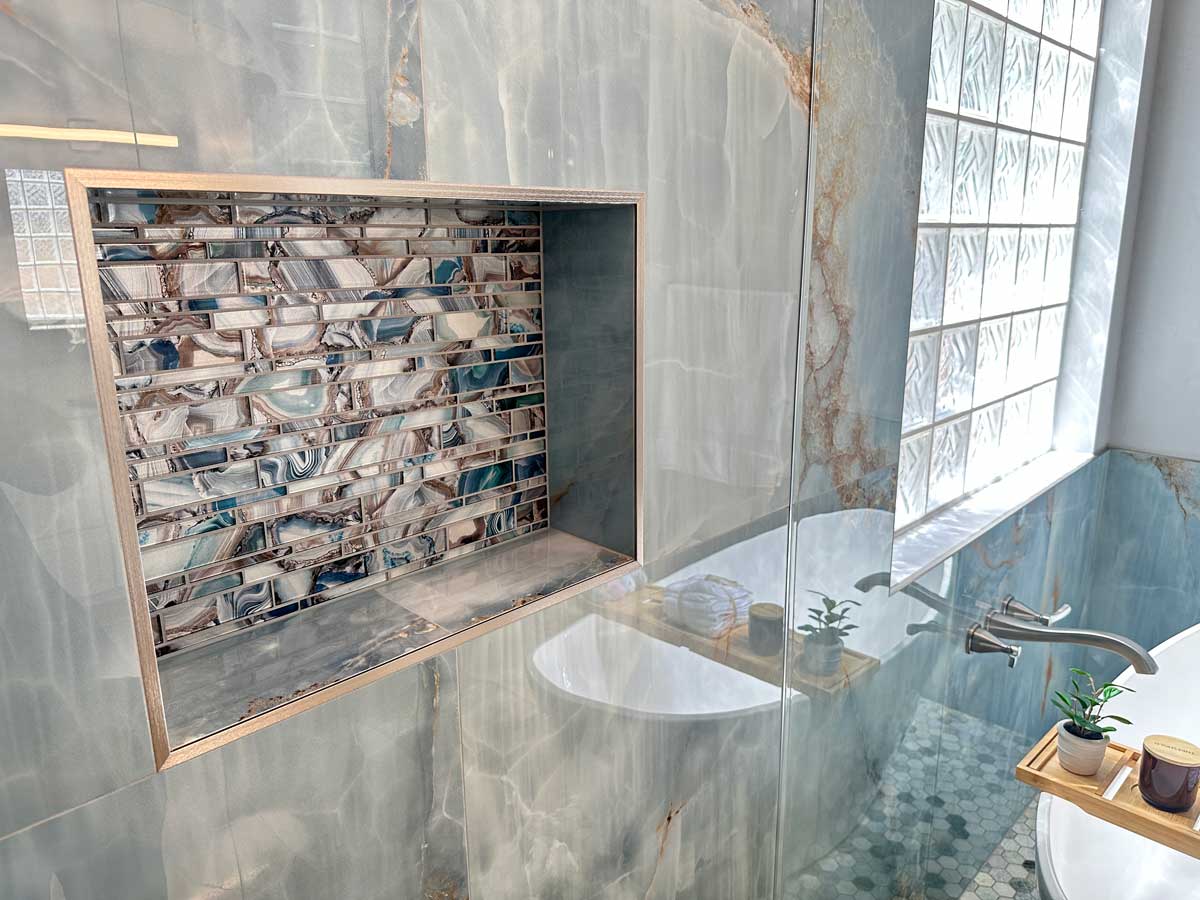 Image of a sleek, modern bathroom storage solutions in Gilbert, AZ, with a custom-built shower niche holding shampoo bottles.